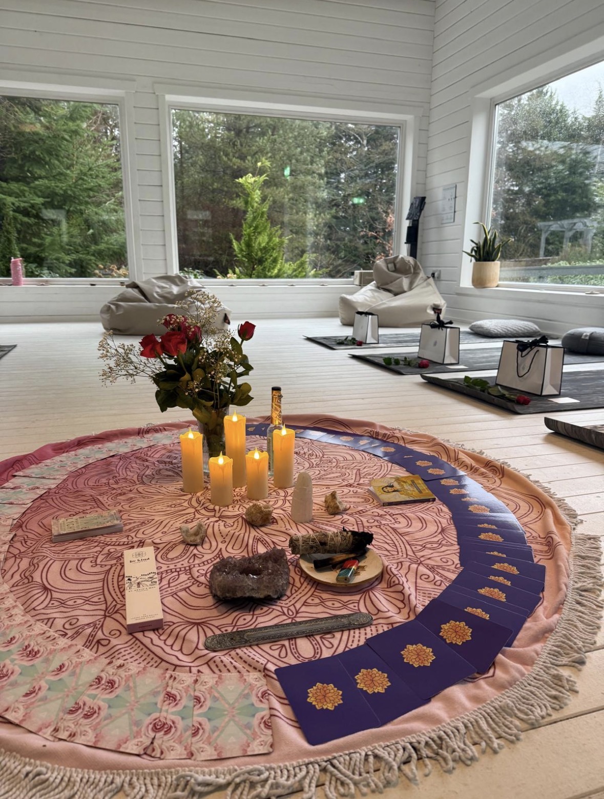 A mandala circle with candles, roses, crystals and tarot cards laid out for ceremony