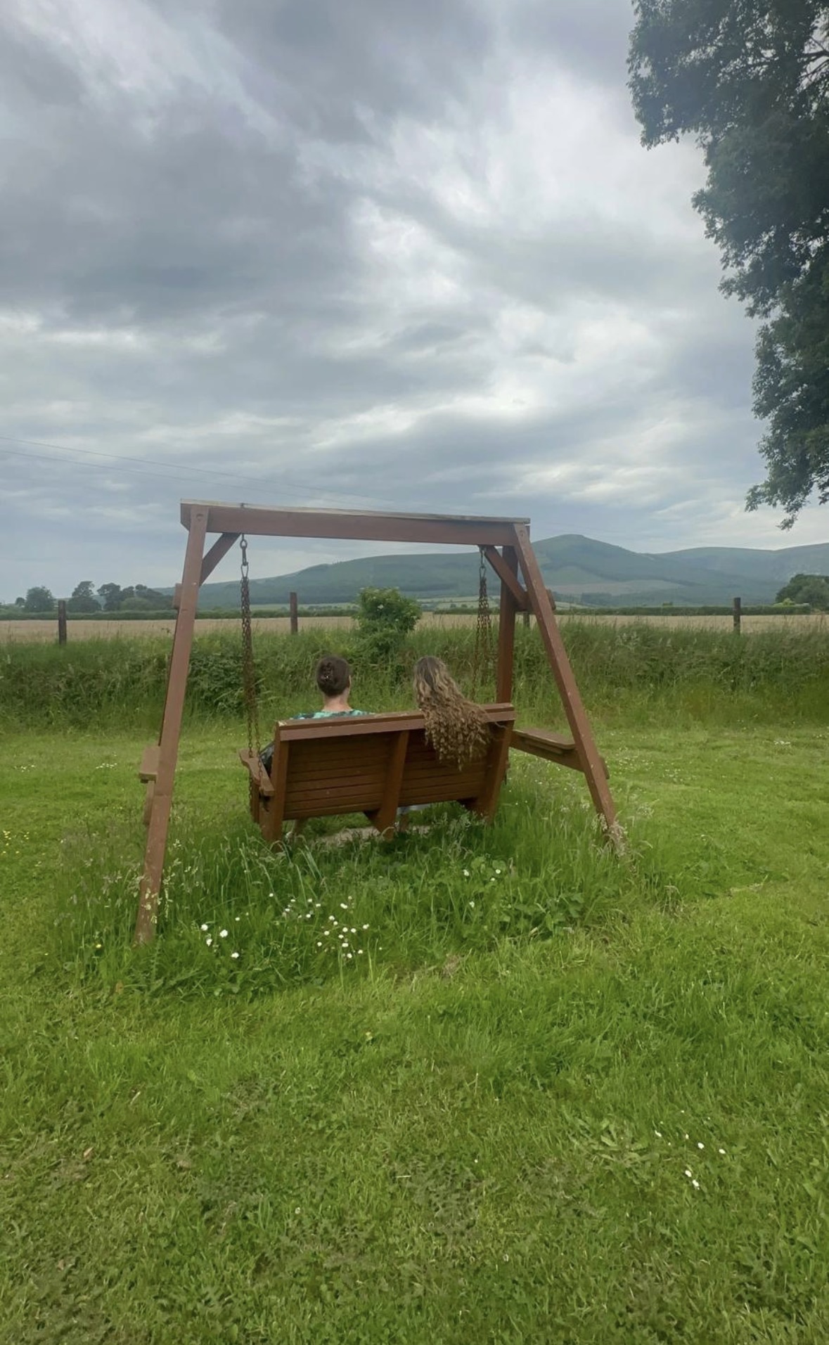 Two guests relaxing on a garden swing overlooking the mountain scenery